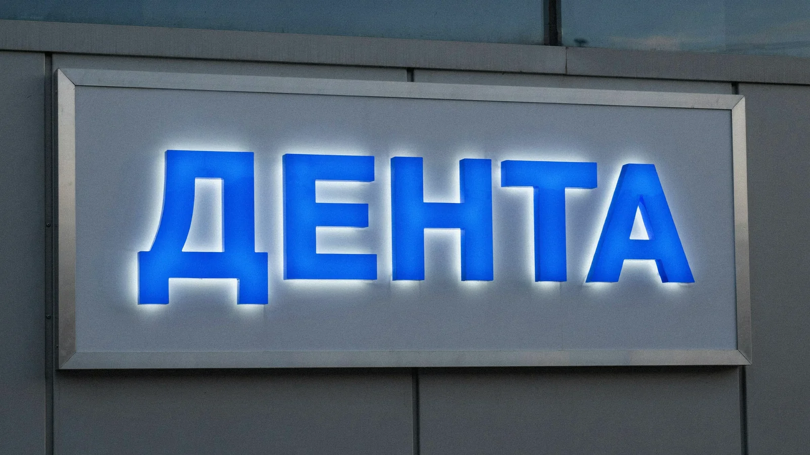 Крупный план вывески стоматологии: световой короб с синими объёмными буквами
